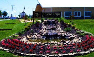 A sign for a funeral home with a waterfall in front of it
