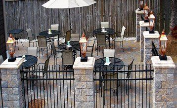 A patio with tables and chairs and umbrellas behind a fence