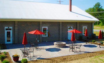 A patio with tables and chairs and red umbrellas in front of a building