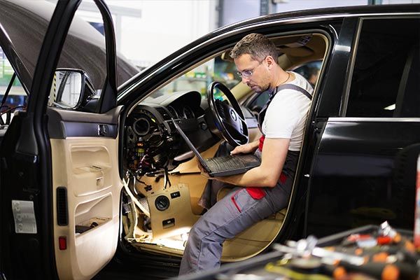 man checking car on laptop