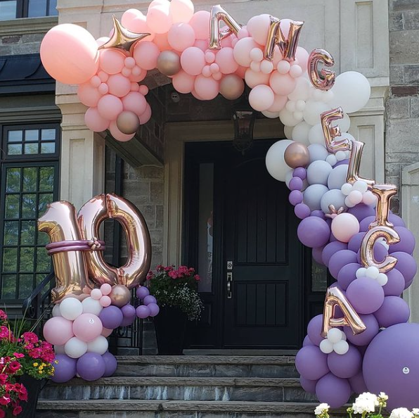 A pink and purple balloon arch with the number 10 on it