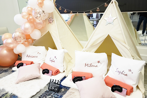 A group of children are sitting in teepees with pillows and balloons.