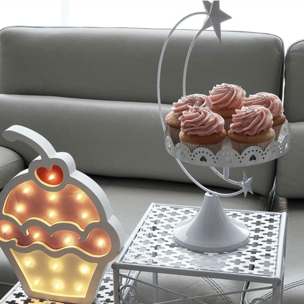 A cupcake shaped light sits on a table next to a plate of cupcakes