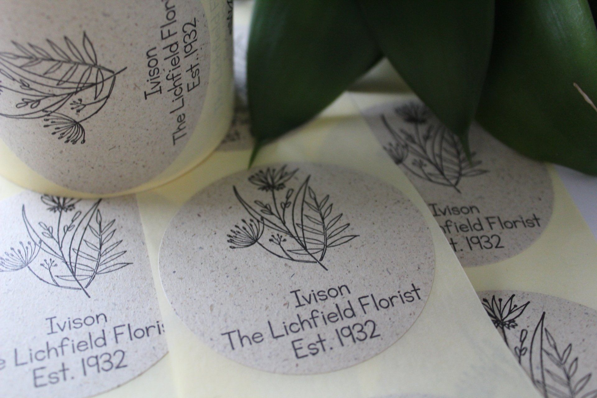 A reel of labels with a black line drawing of flowers on them sitting on a table.