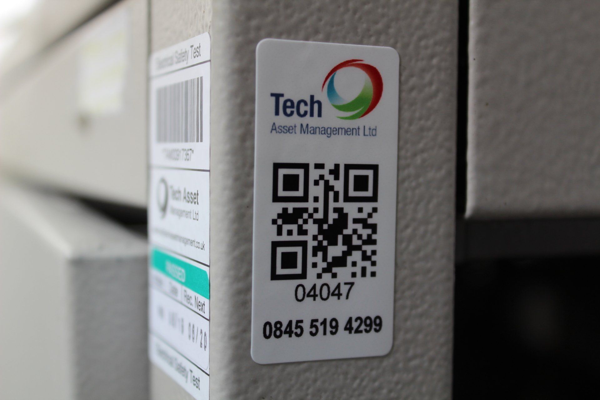 Close up of a QR code product label fixed to a machine next to a barcode Electrical Safety Test label
