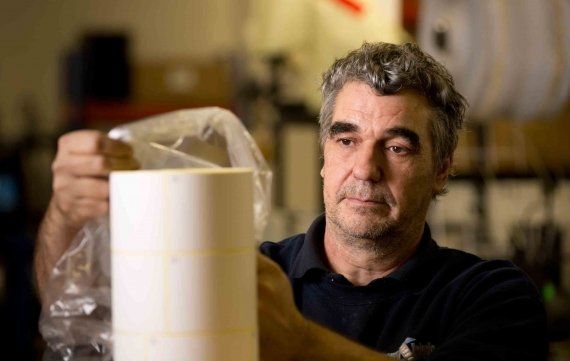 Tim placing a clear bag over a finished reel of plain white labels.