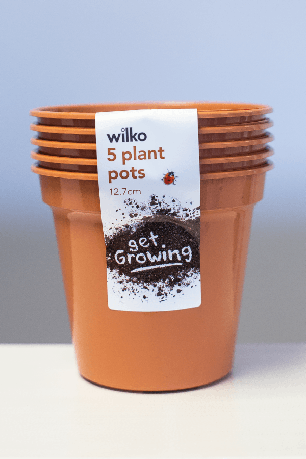 A stack of 5 plant pots on a table with a perfectly printed label down the side which also keeps them together