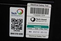 Close up of a QR code product label fixed to a machine next to a barcode Electrical Safety Test label