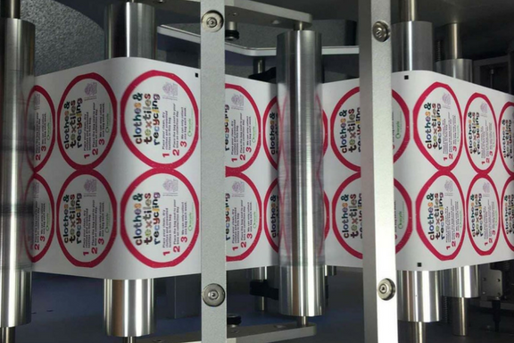 Brightly coloured 'Clothes & Textiles Recycling' labels being produced on the Trojan Press