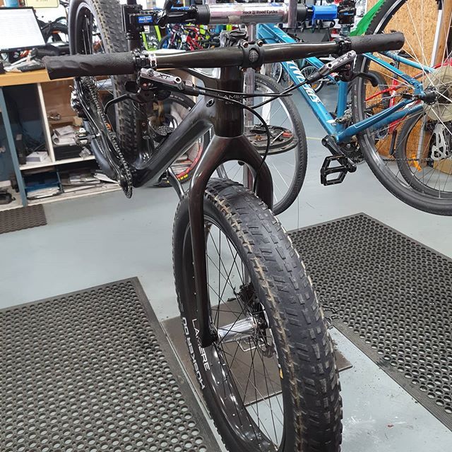 Black fat tire bike, front view, in a bike shop. Wide handlebars, thick tires.