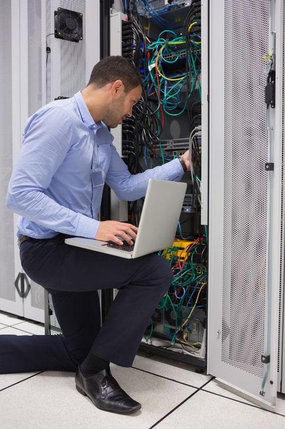 A man with a laptop moving wires in a server rack