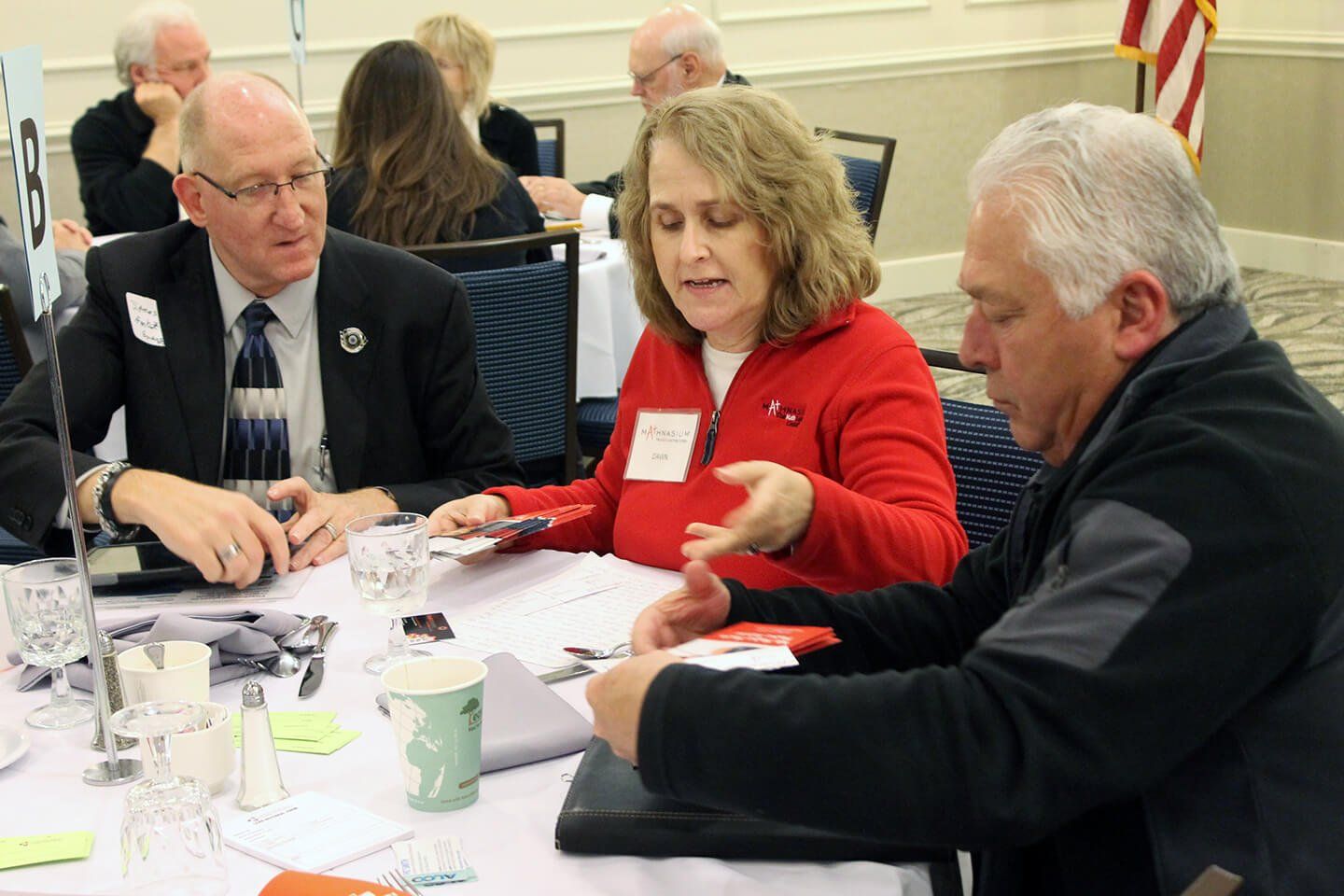 Three people at a table, there are refreshments on the table