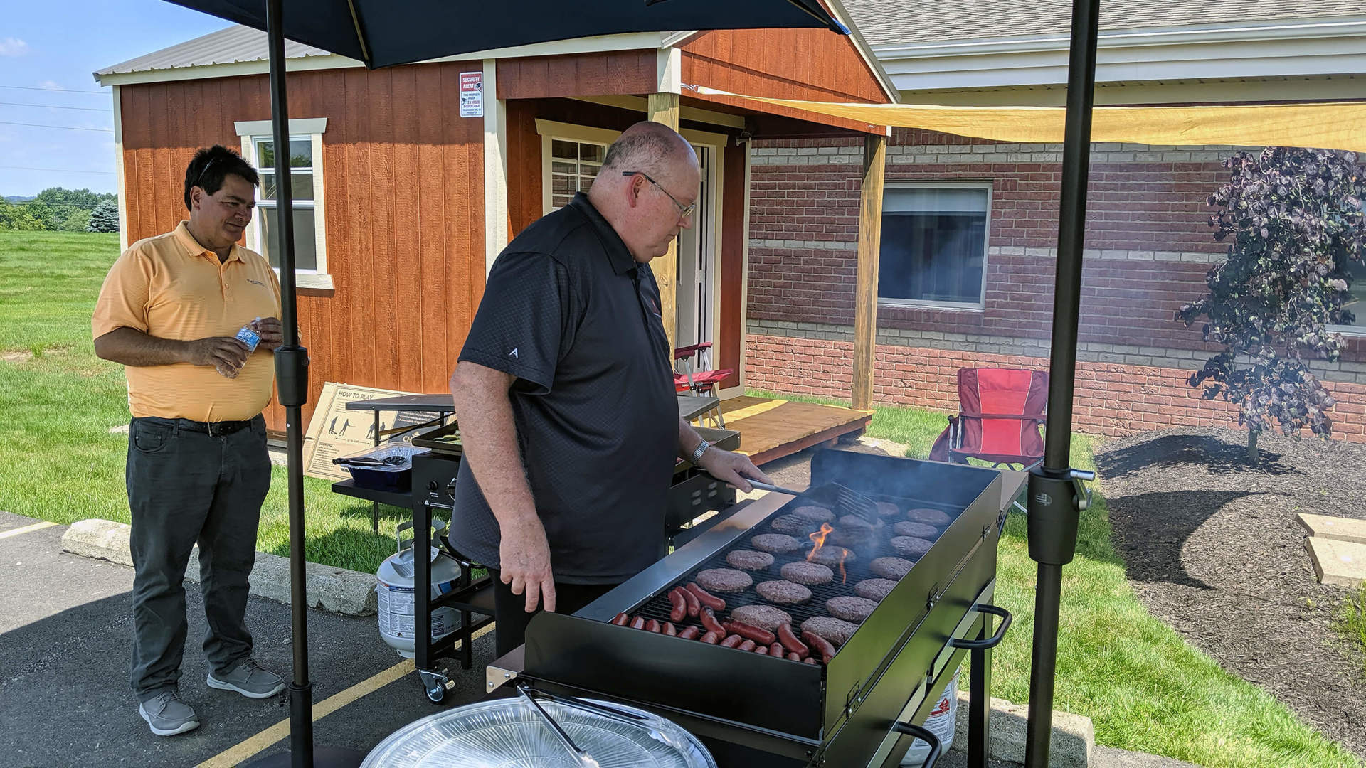 One employee at the grill, another is behind him