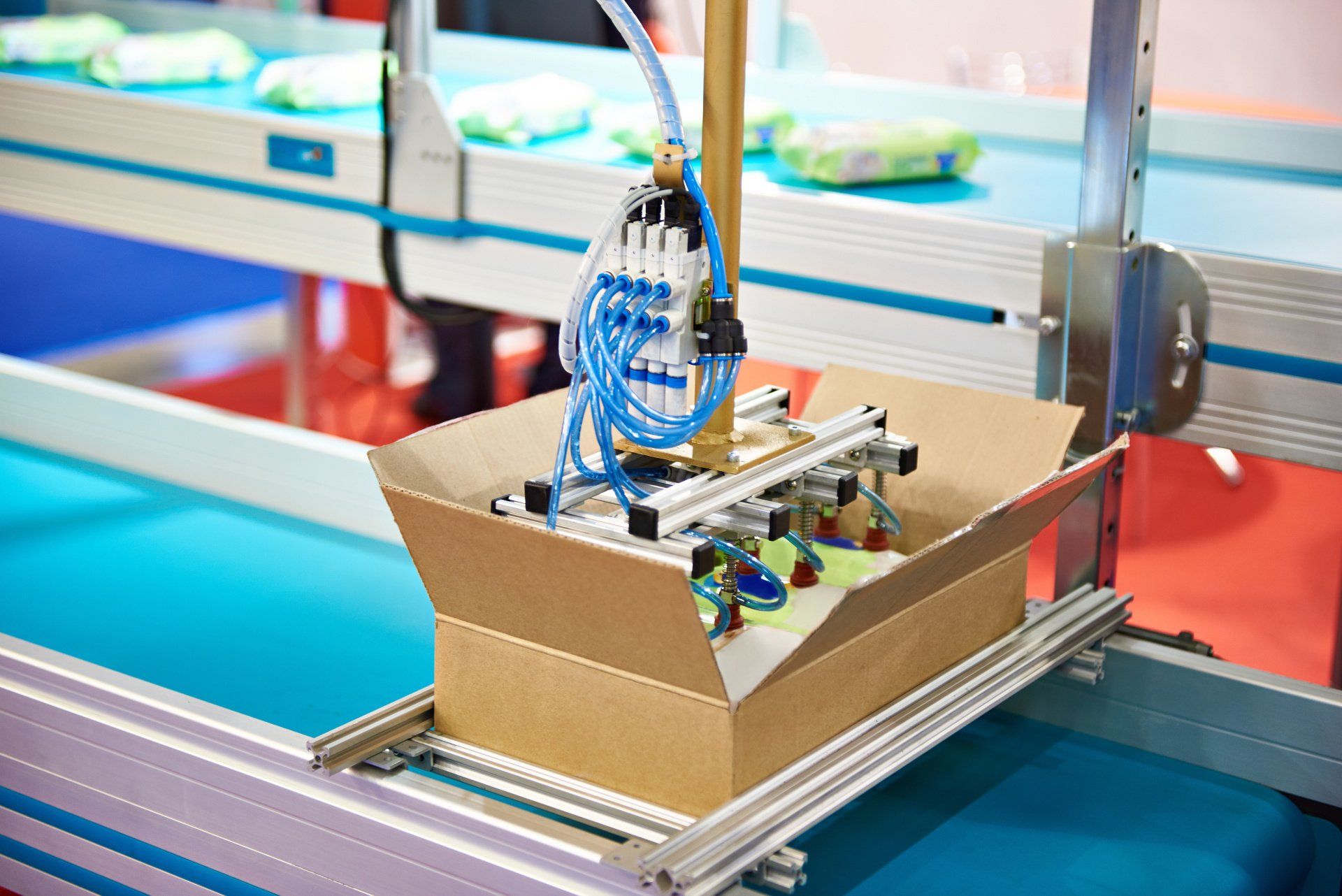 A machine with suction cups placing an object in a cardboard box.