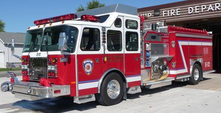 A red fire truck is parked in front of a building that says Ira Township Fire Department.