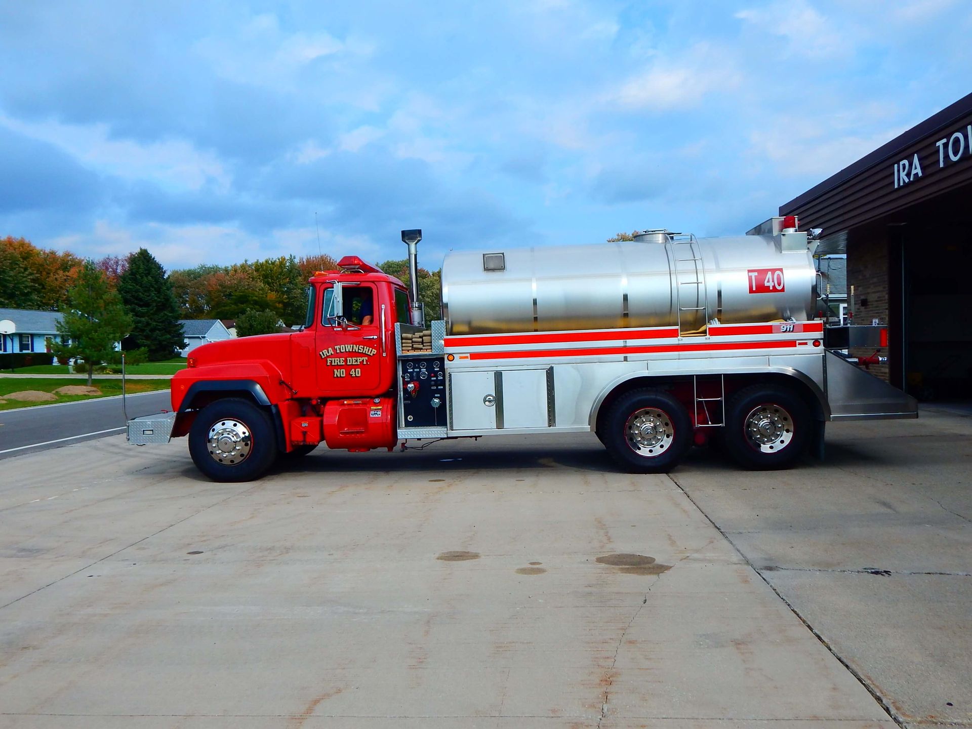 A red truck is parked in front of a building that says Ira Township Fire Department.