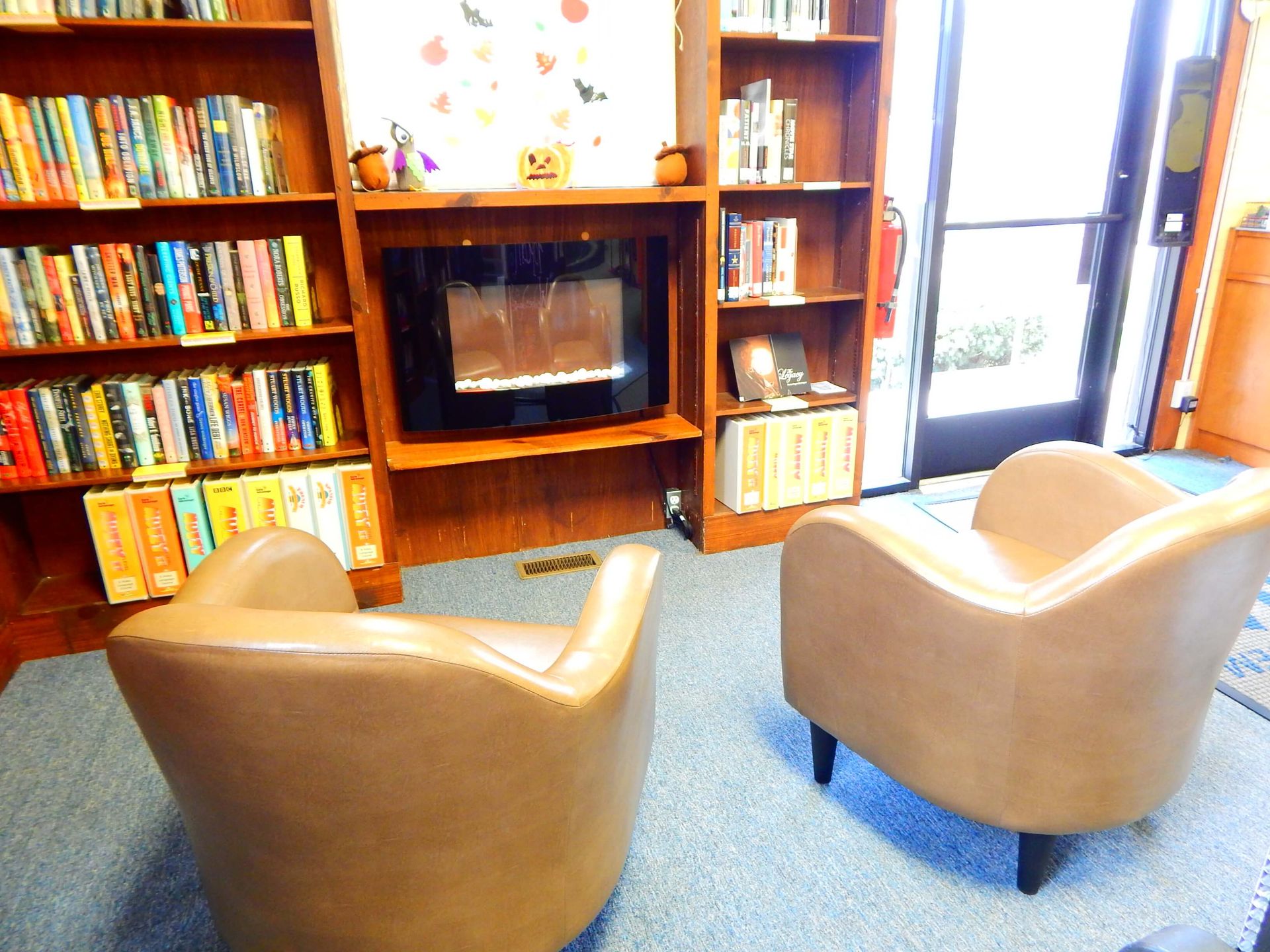 Two chairs in front of a fireplace in a library.