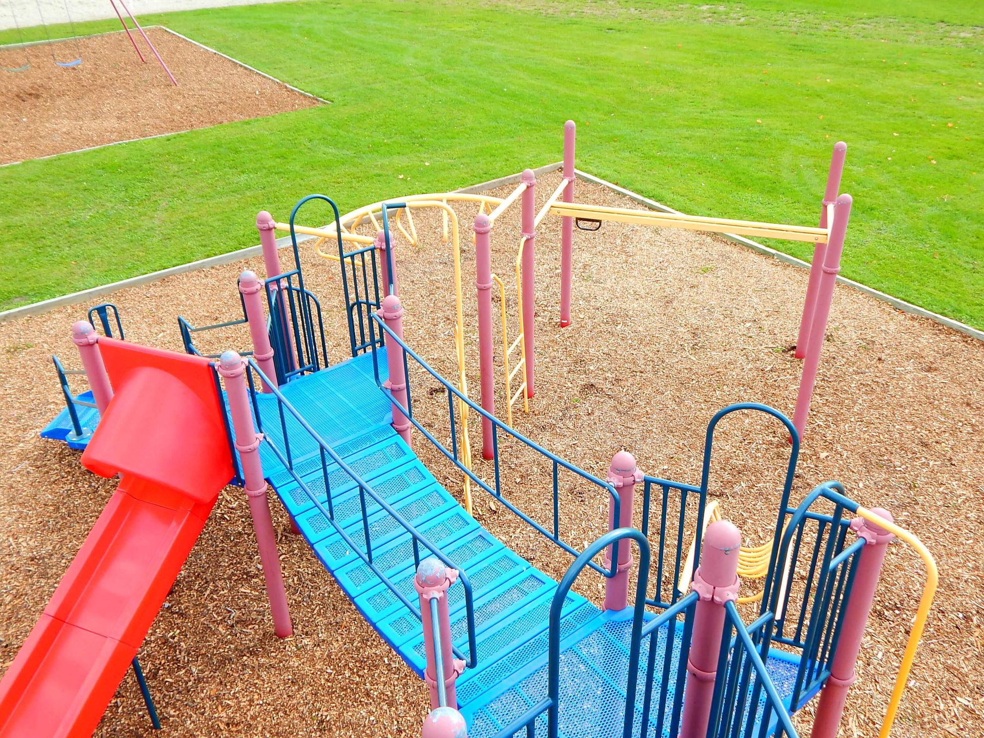 An aerial view of a colorful playground with a slide and a bridge.