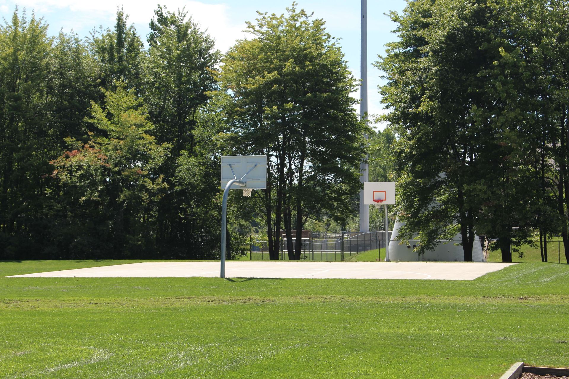 A basketball court in a park with trees in the background