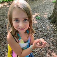 A picture of a girl in the woods smiling.