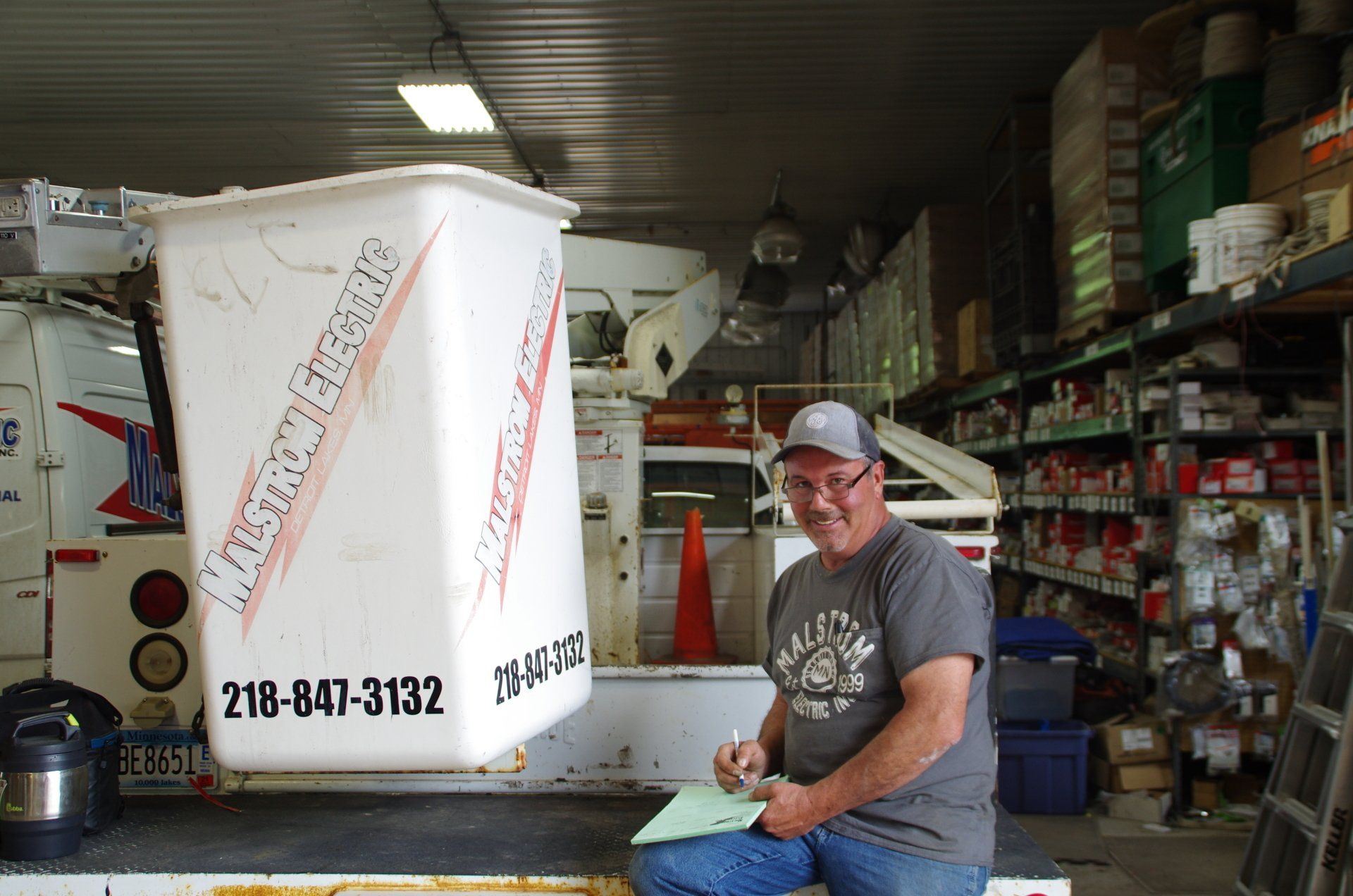 A man is sitting in front of a white bucket with the number 218-847-3132 on it