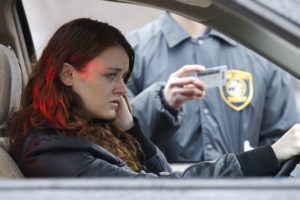 Woman in car being approached by police officer, pulled over.