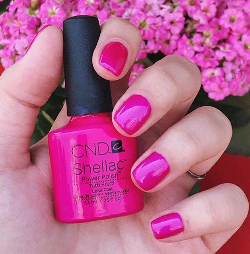 A woman is holding a bottle of cnd shellac nail polish