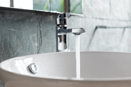 Picture of a silver bathroom faucet with running water coming out.