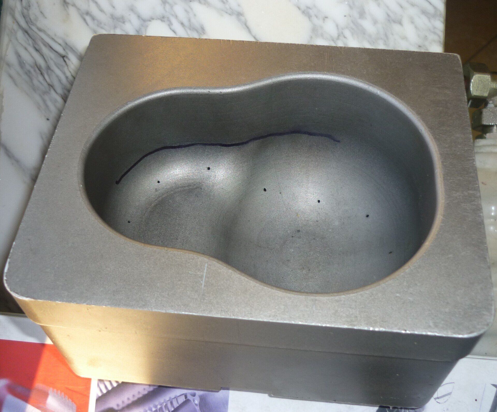 Stampo in metallo grigio con interno sagomato, potenzialmente adatto alla fusione.