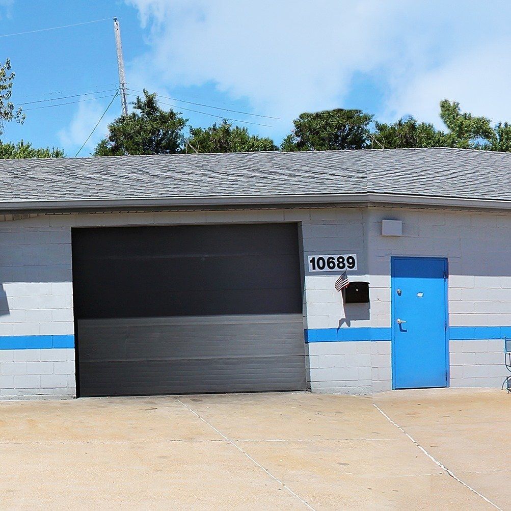Gray garage with bright blue door and mailbox, house number 10689, under a clear sky