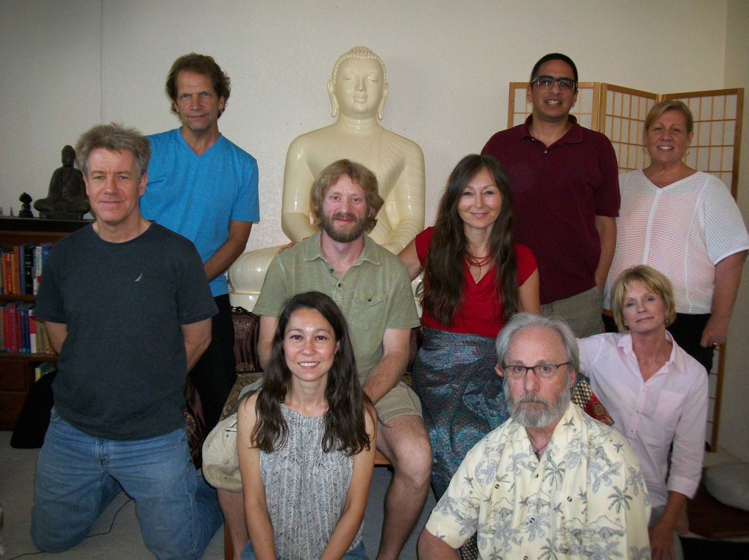 Group of people posing with a statue indoors; several are smiling; neutral expressions.