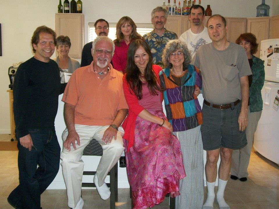 Group of people gathered in a kitchen. Individuals smiling at the camera, posing for a photo.