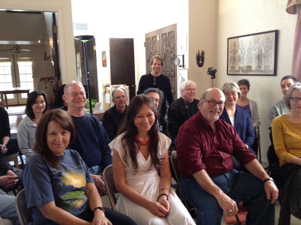 Group of people seated, likely at a meeting or presentation. Some smile. Interior setting.