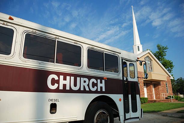 A church bus is parked in front of a church