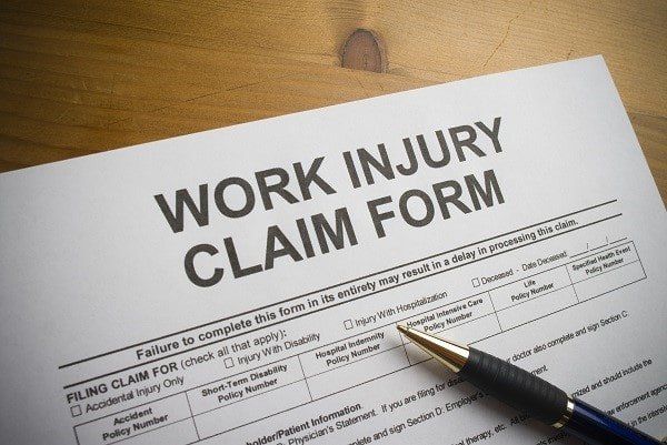 A work injury claim form with a pen on it