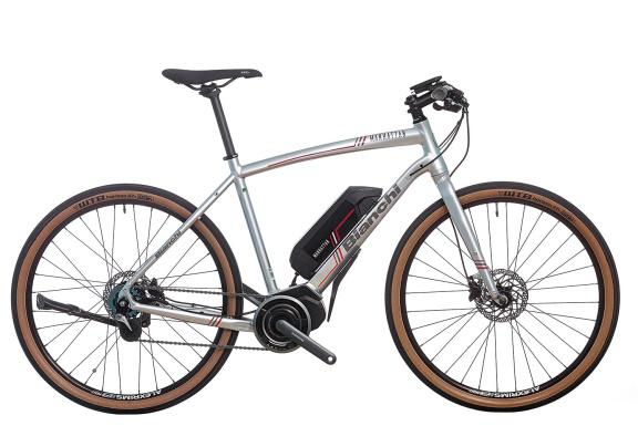 E-bike Bianchi color argento con pneumatici marroni e batteria nera su sfondo bianco.