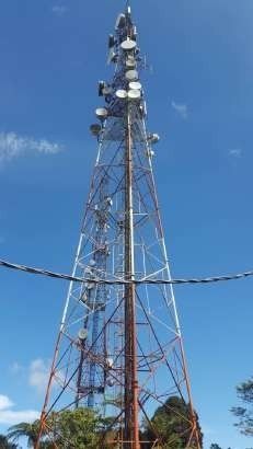 Tall communications tower with antennas against a blue sky.