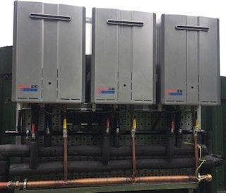 a row of water heaters with copper pipes attached to them