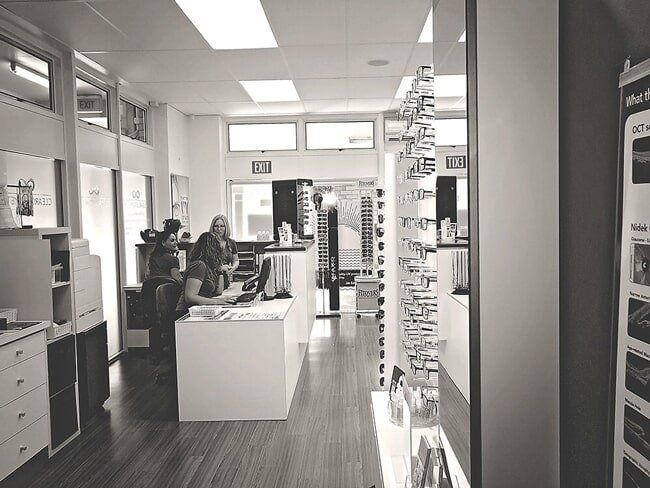 A black and white photo of a woman sitting at a desk in a store.