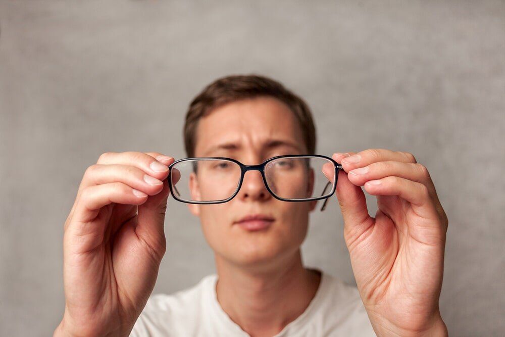 Man Holding Glasses - Clear Optometry In Bargara, QLD Man Holding Glasses - Clear Optometry In Bargara, QLD