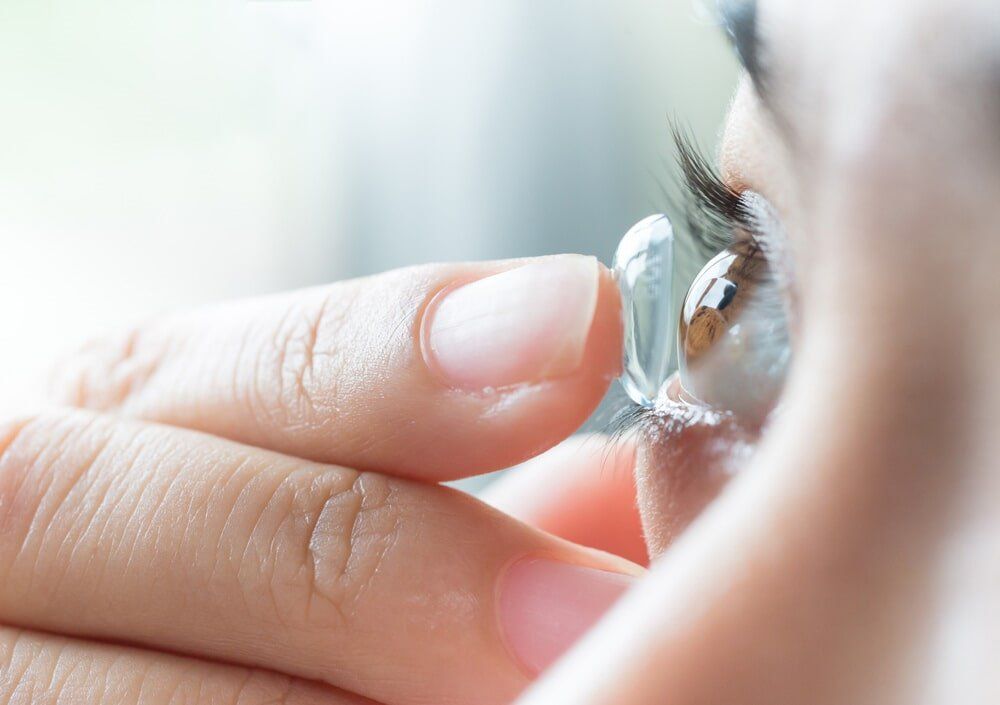 A close up of a person putting a contact lens in their eye.