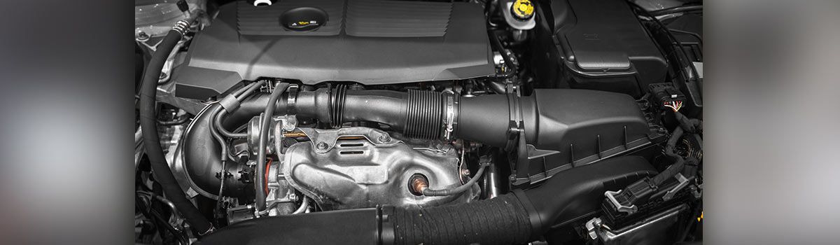 Car engine bay with black components and piping.