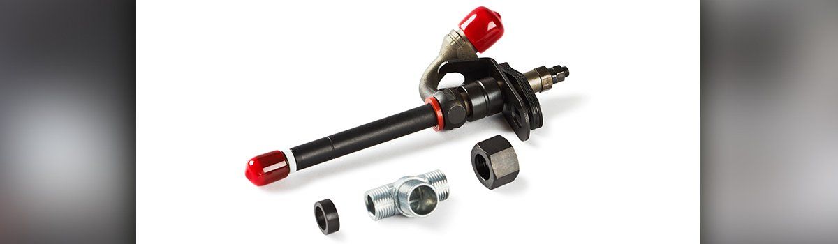 A diesel fuel injector and its components, laid out on a white surface. The injector is black with red caps and fittings.