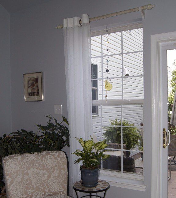 A living room with a chair and a potted plant in front of a window