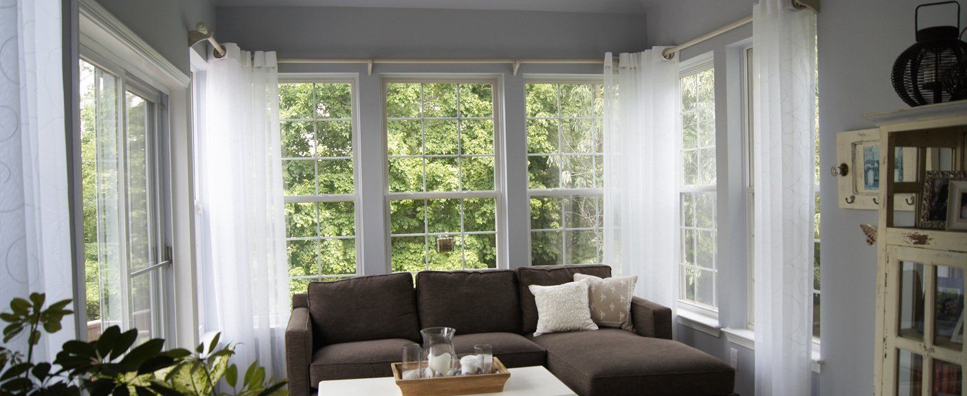 A living room with a couch , coffee table , and lots of windows.