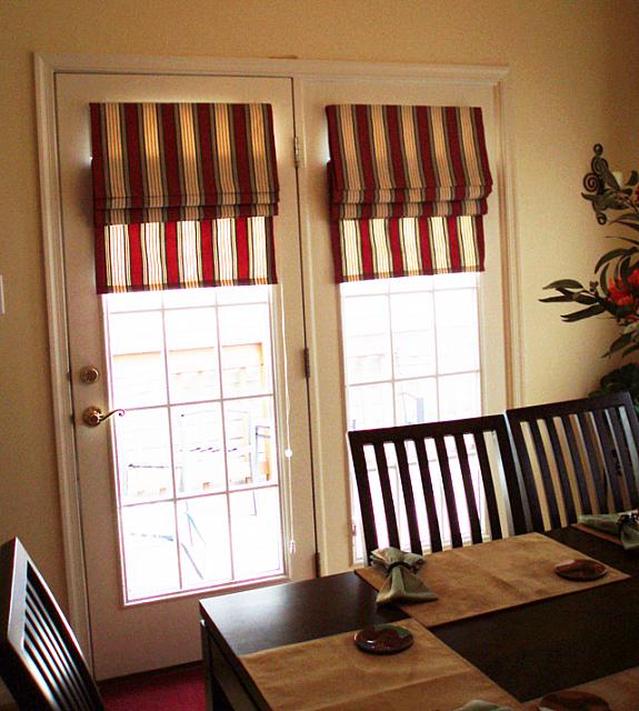 A dining room with a table and chairs and striped curtains