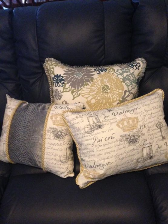 Three pillows are sitting on a black leather couch and one of them says valencia