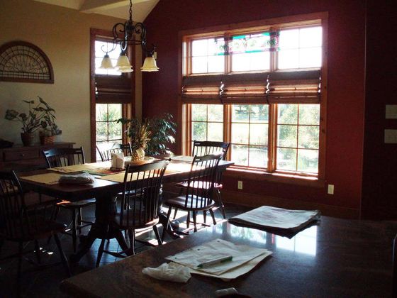 A dining room with a table and chairs and lots of windows