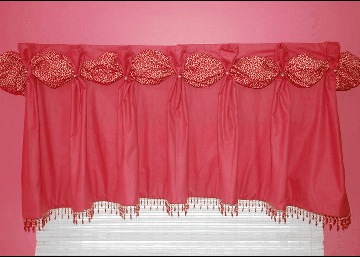 A red curtain is hanging on a window with a pink wall behind it