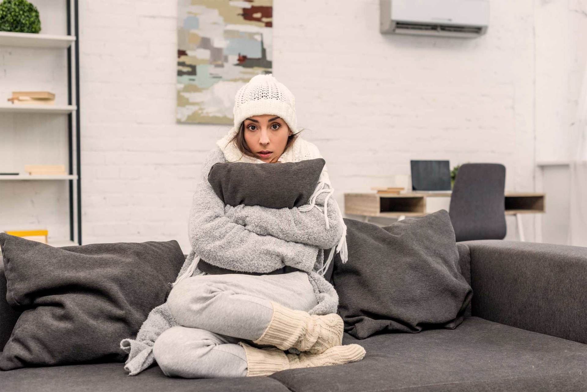 Young Woman in Warm Clothes Sitting on Couch — Ashland, KY — ArTron Heating & Air Conditioning